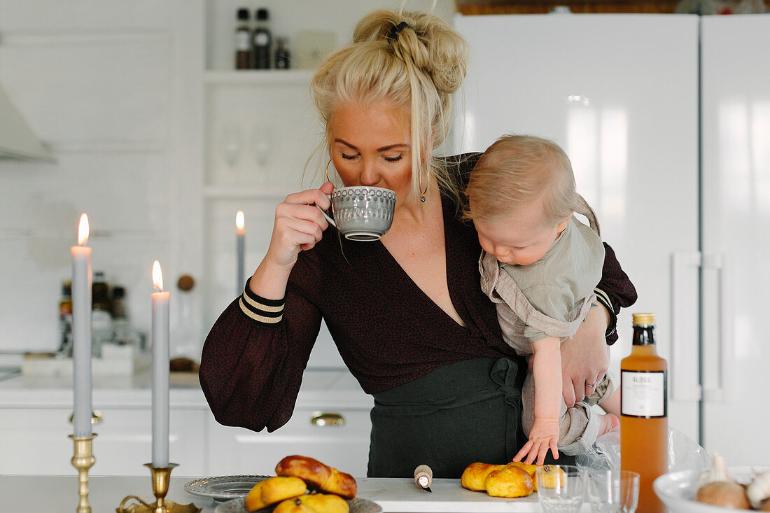 Mutter mit Kleinkind im Arm trinkt Kaffee