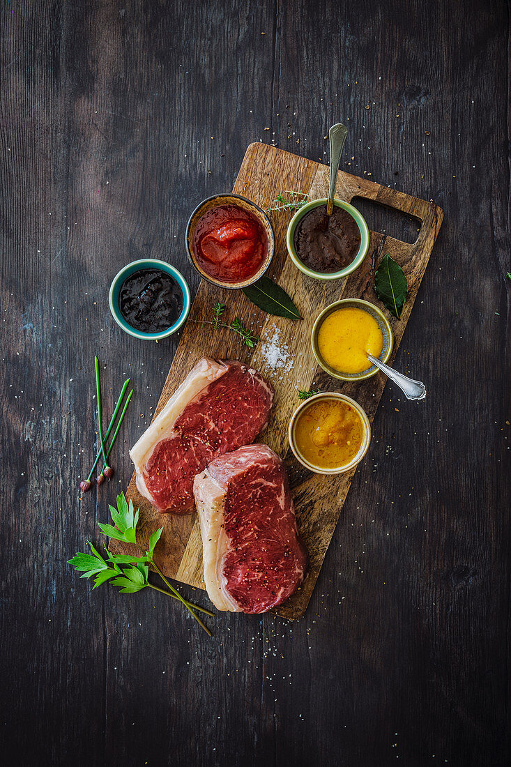 Various barbecue sauces alongside fresh rump steaks