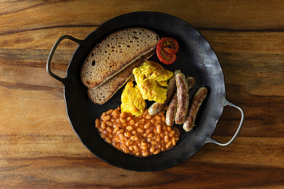 Englisches Frühstück mit Baked Beans, Rührei, Würstchen und Tomate