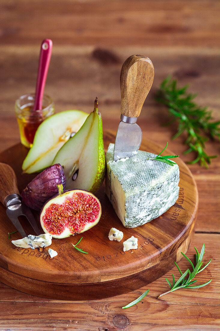 Blue cheese, figs, pears and honey on a wooden board