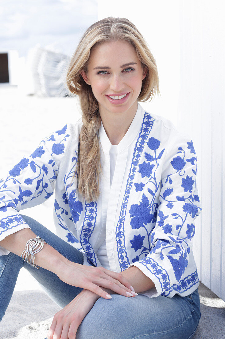 Blonde, langhaarige Frau in Jeans und weiß-blauer Jacke