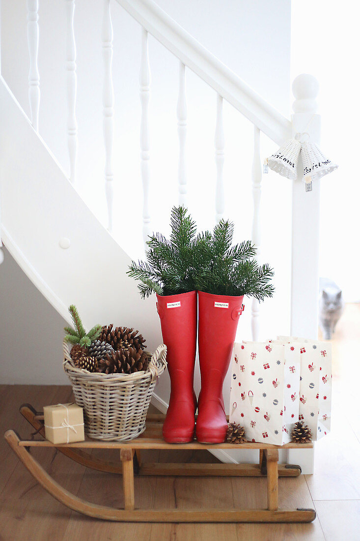 Schlitten mit weihnachtlich dekorierten Gummistiefeln vor Treppe
