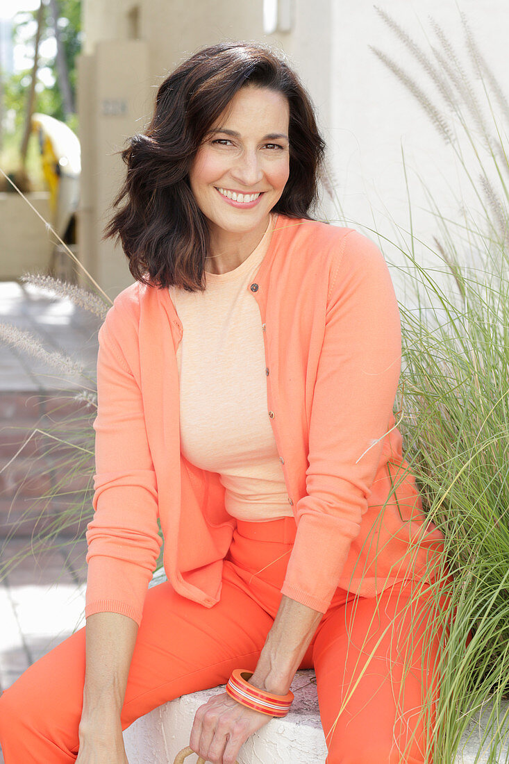 An older brunette woman wearing a salmon-coloured outfit