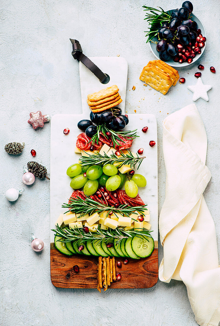 Christmas cheese platter with grapes, cucumber, and crackers in the shape of a fir tree