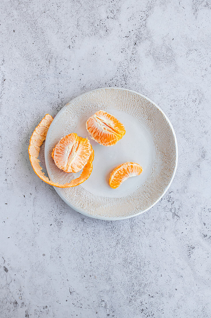 Geschälte Honeygold-Mandarine auf dekorativer Keramikplatte