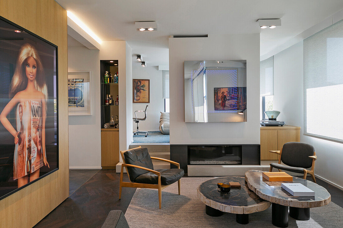 Designer table with petrified wood top and armchair in front of fireplace in split-level living room with large-format photo on wooden wall