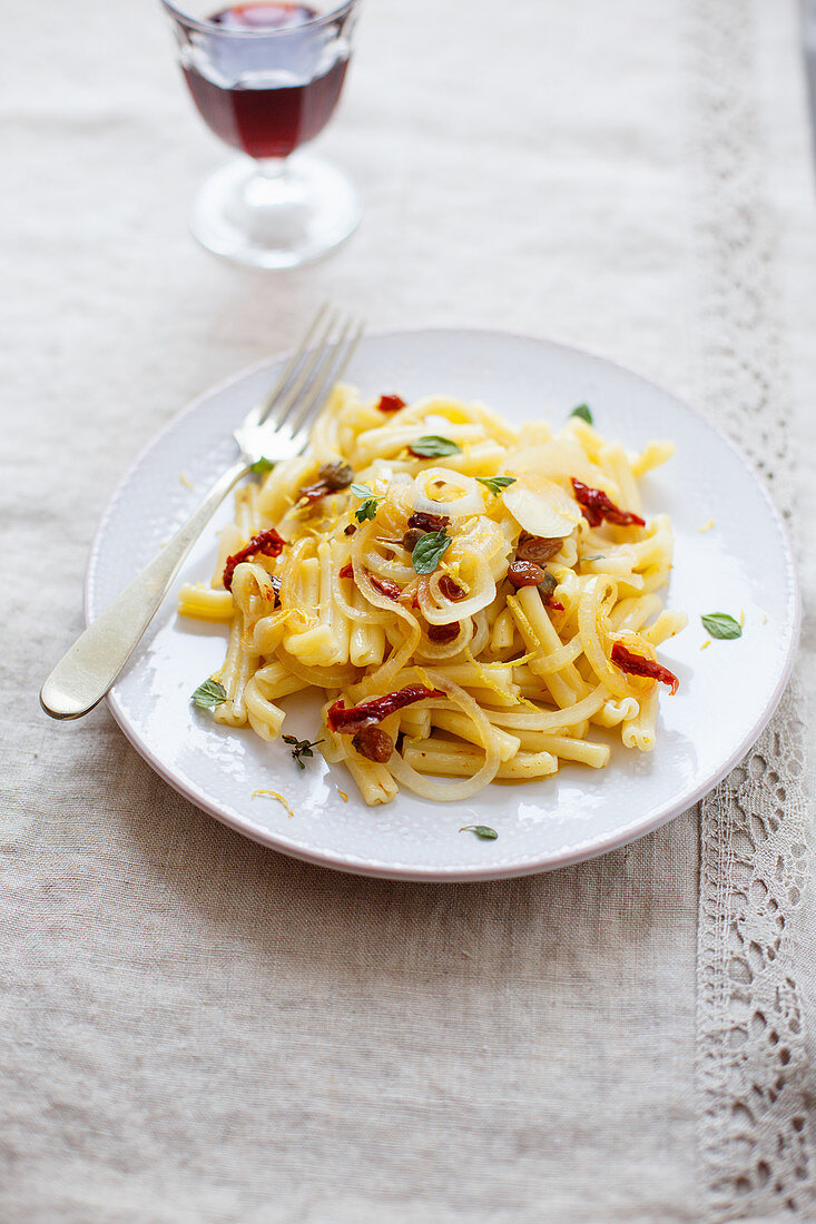 Short pasta with onion, dried tomato, lemon zest, raisins and mint