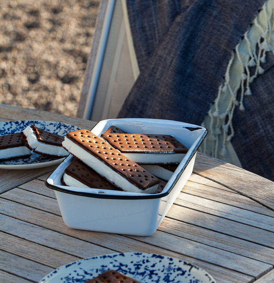 Schokoladen-Vanilleeis-Sandwiches in Emailleschale auf Tisch im Freien