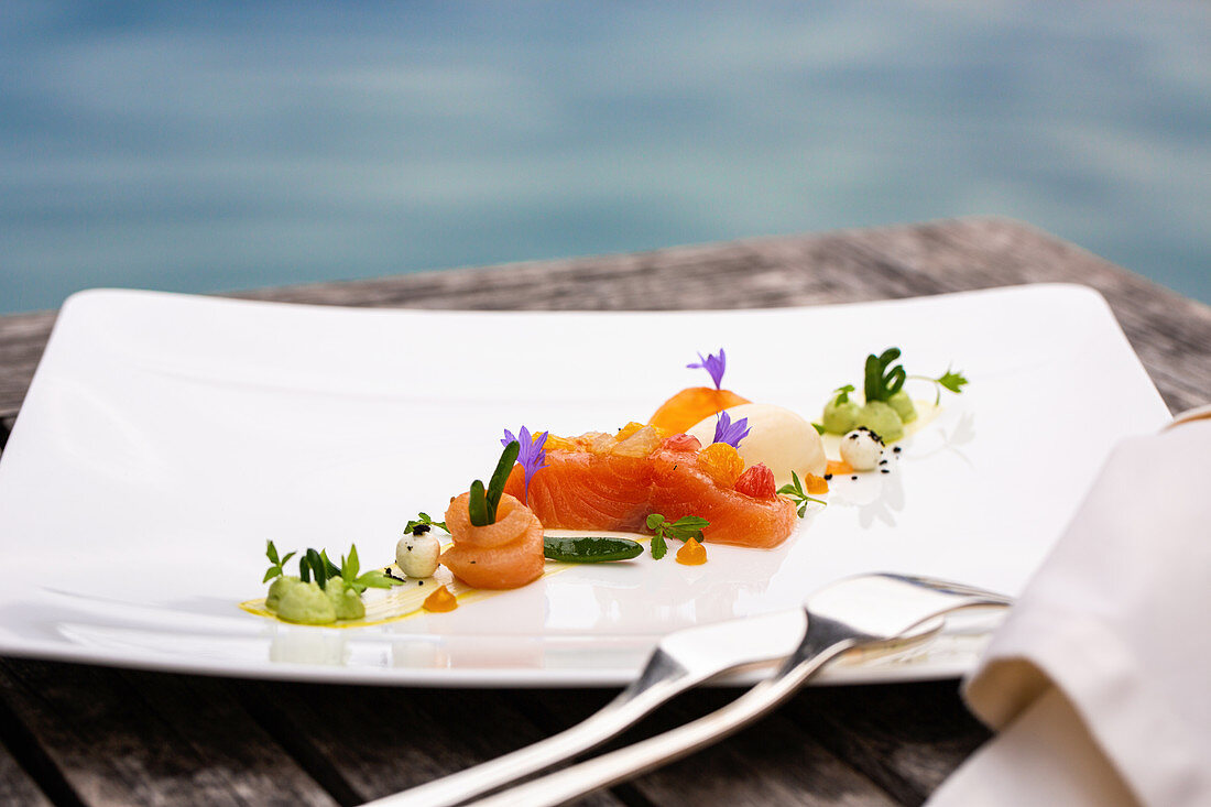 Char dish served on wooden table overlooking a lake