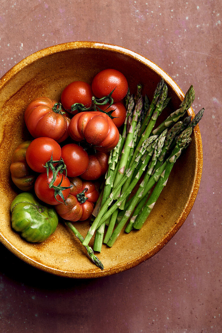 Tomatoes and asparagus in earthenware bowl