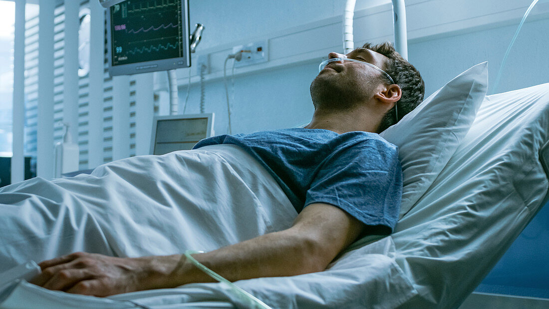 Ill man suffering while lying in a hospital bed