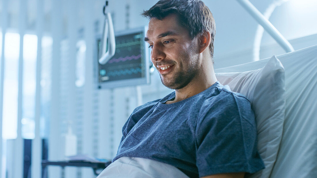 Sick patient using a laptop in a hospital bed