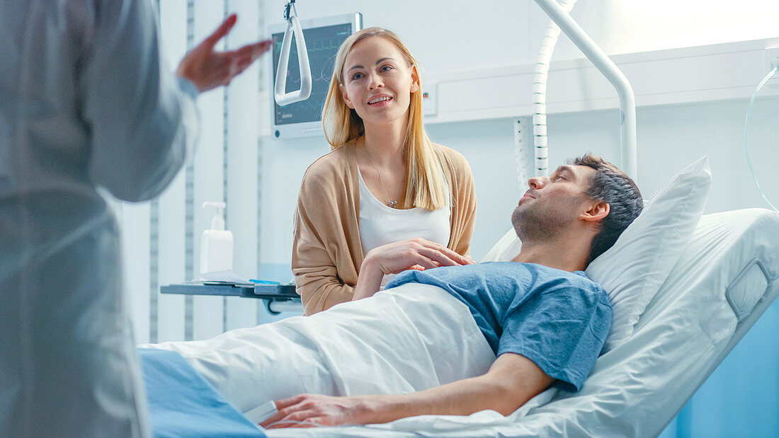 Wife sitting next to a patient lying in bed
