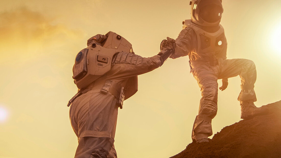 Two astronauts helping each other to climb a hill