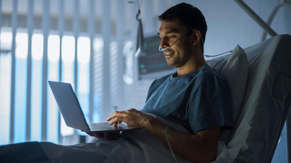 Recovering patient using a laptop in hospital