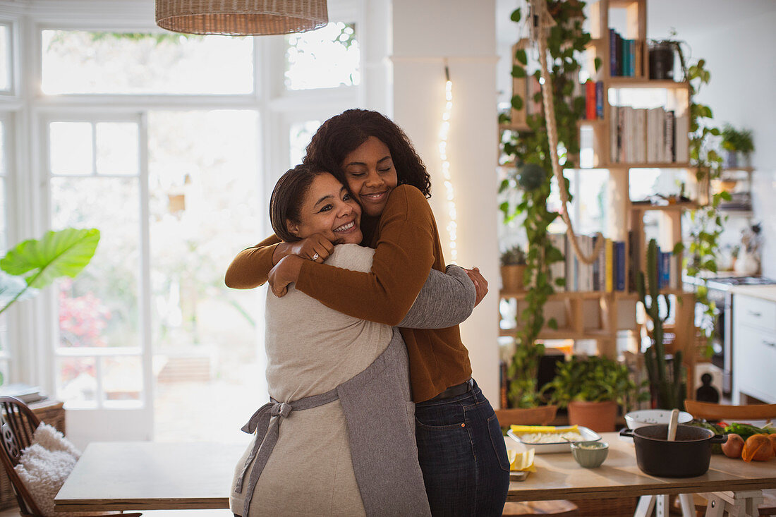 Happy mother and daughter hugging at home