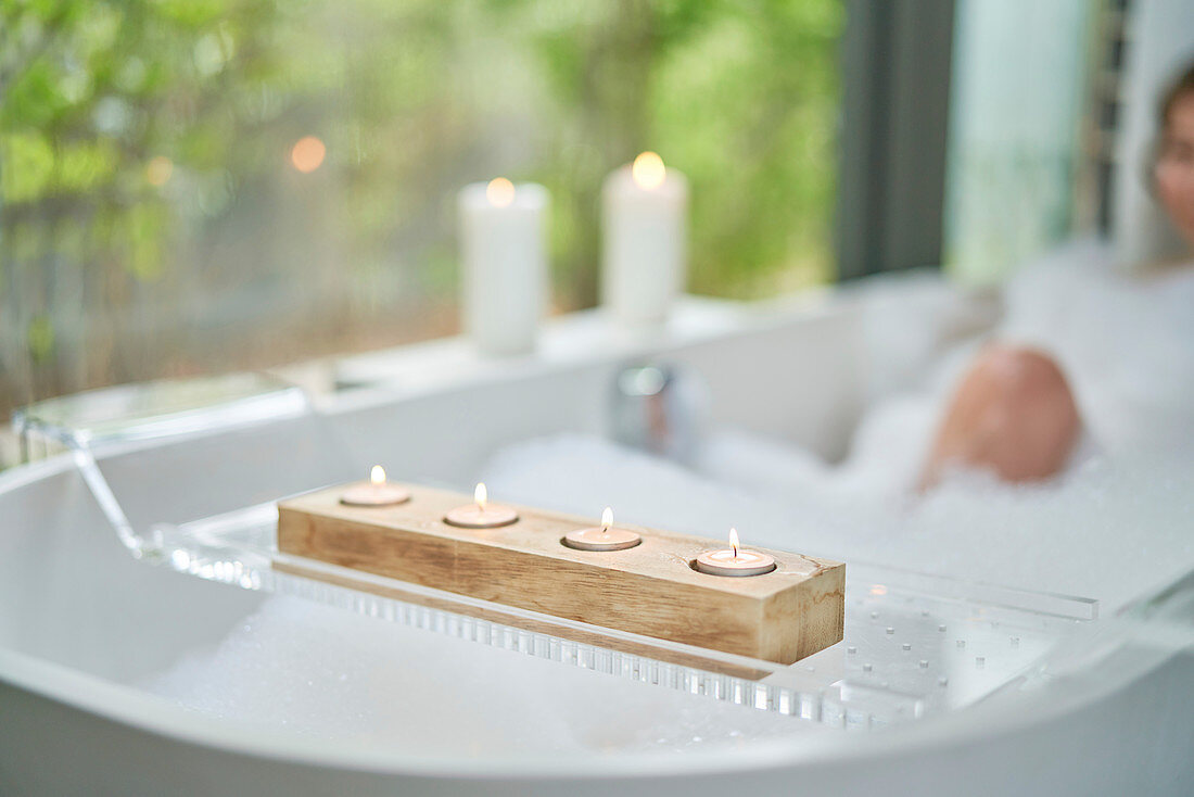 Tea light candles on tray over bubble bath