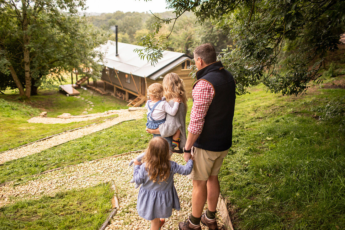 Family walking on path above cabin in woods