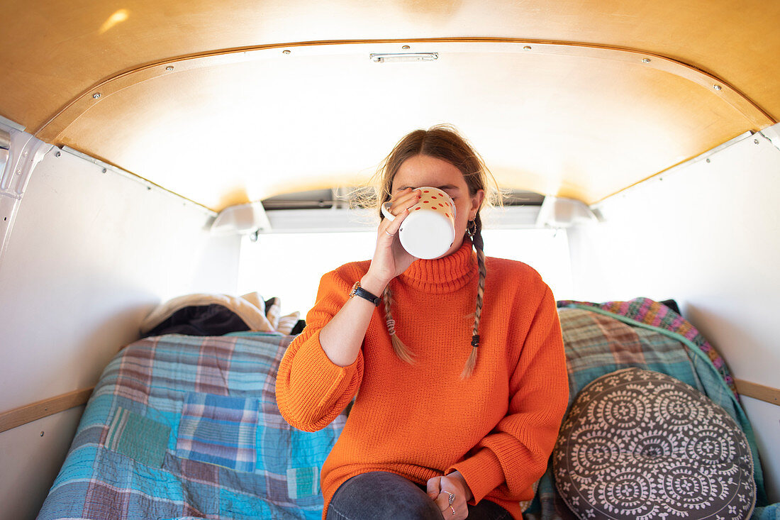Young woman drinking tea in camper van