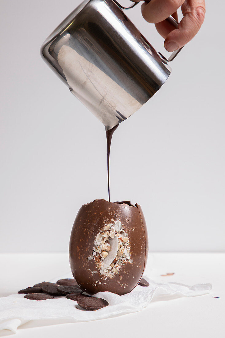 A hand pouring melted chocolate in to a Chocolate Easter egg