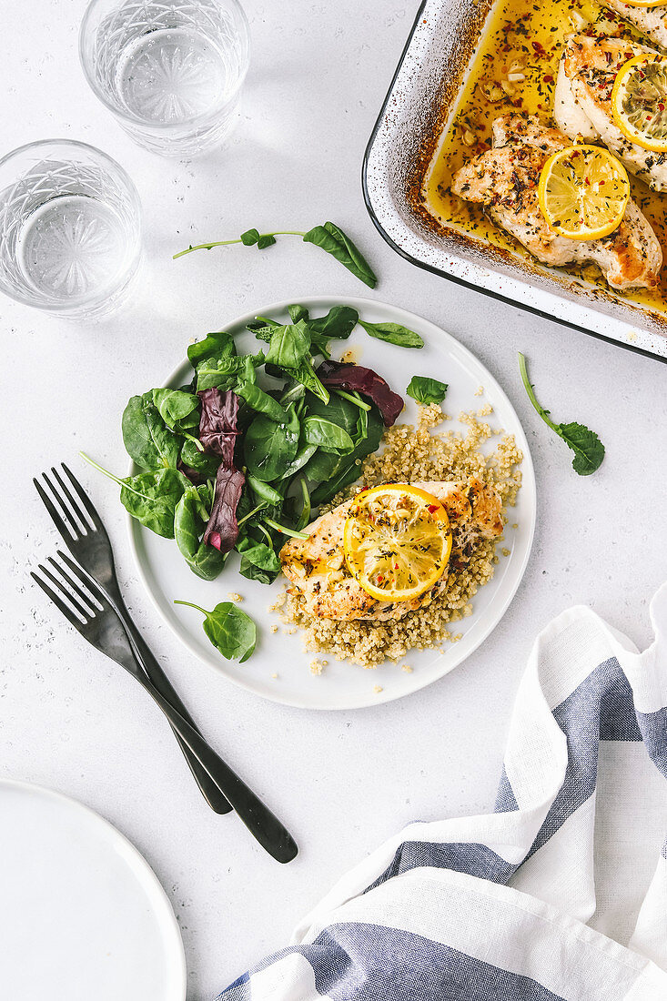 Baked chicken breast plated with lemon and green salad