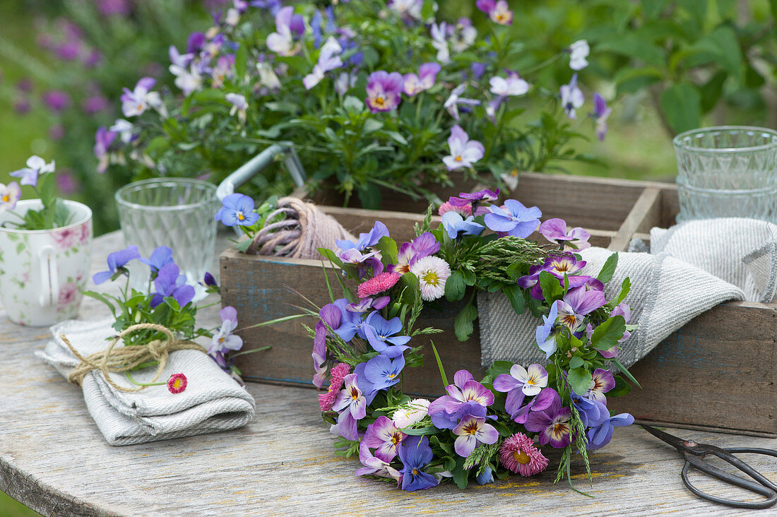 A Small wreath made of horned violets, daisies, and grass