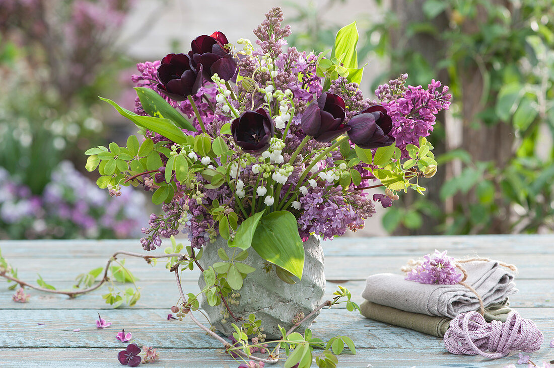 Spring bouquet of lilacs, black tulips, lilies of the valley, and chocolate vine