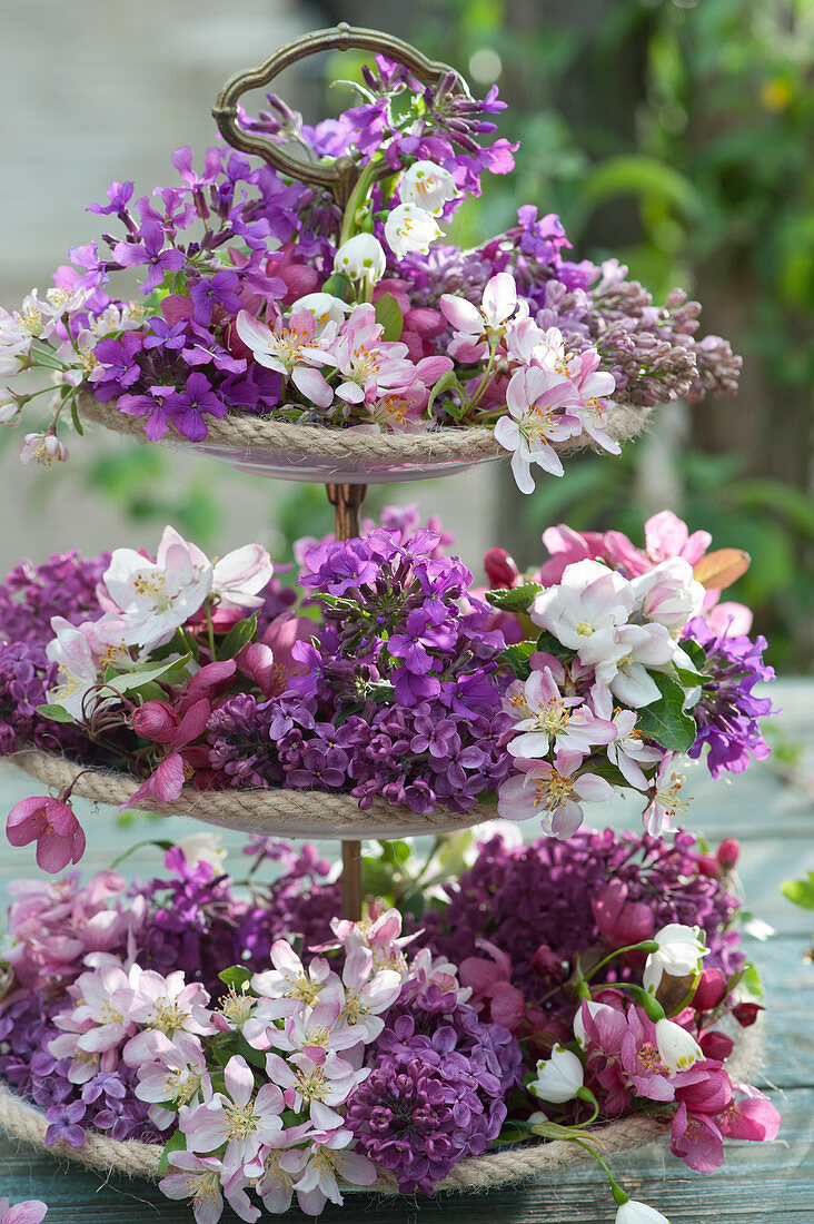 Frühlings-Tischdekoration auf Etagere mit Fliederblüten, Zierapfelblüten und Blüten vom Silberblatt