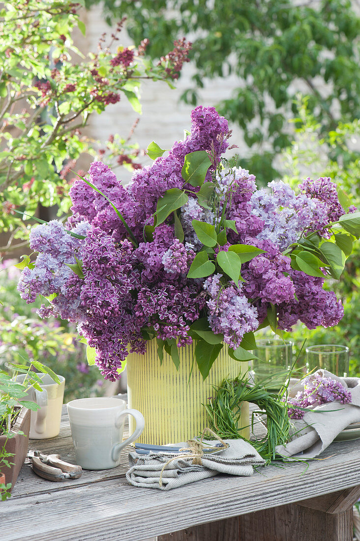 A lush bouquet of lilacs and a grass wreath as a table decoration