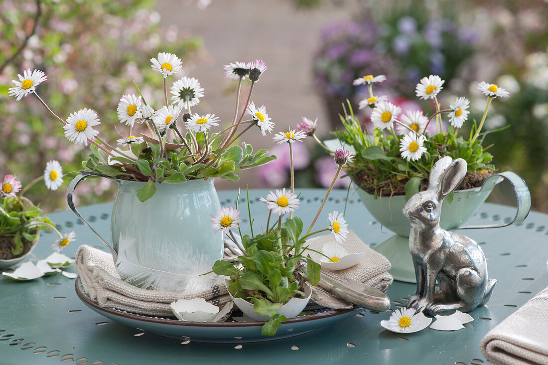 Osterdeko mit Gänseblümchen in Blechgefäßen, silberner Osterhase