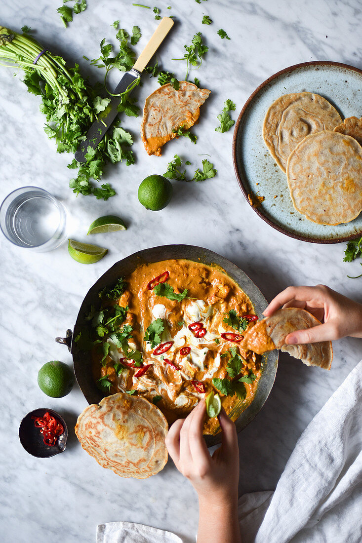 A woman eating a spicy curry, surrounded by ingredients