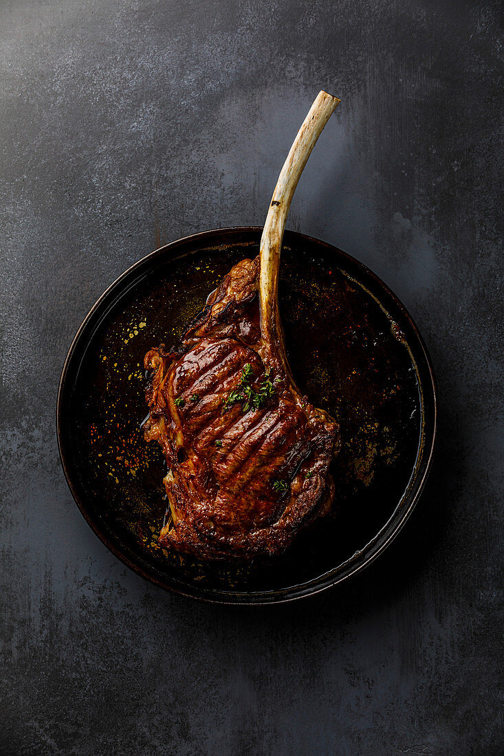 Gegrilltes Tomahawk Steak auf dunklem Hintergrund