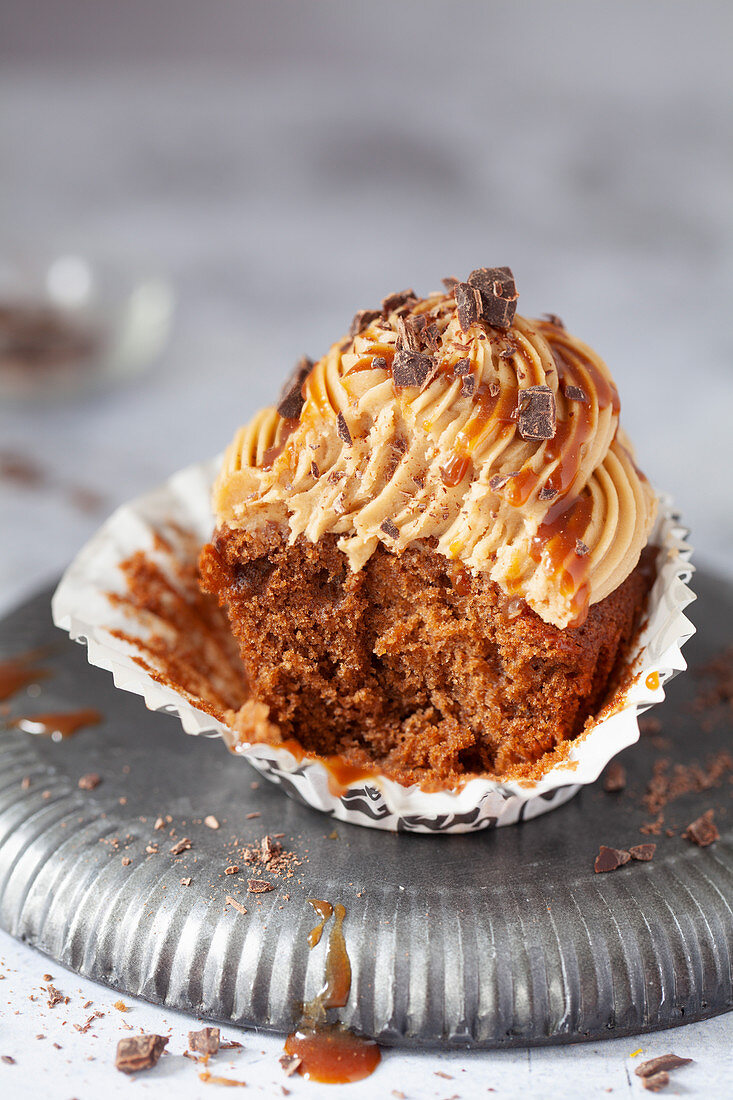 A part eaten mocha cake in its paper wrapper