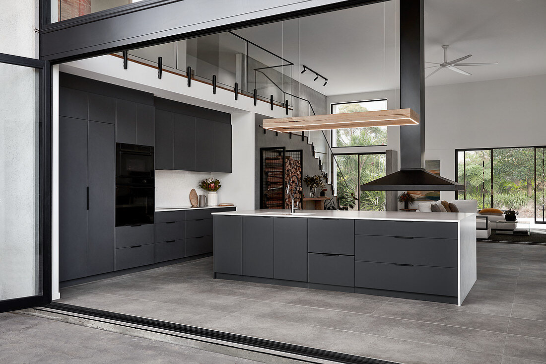 Schwarze Küche mit Kücheninsel in offenem Wohnraum mit Galerie