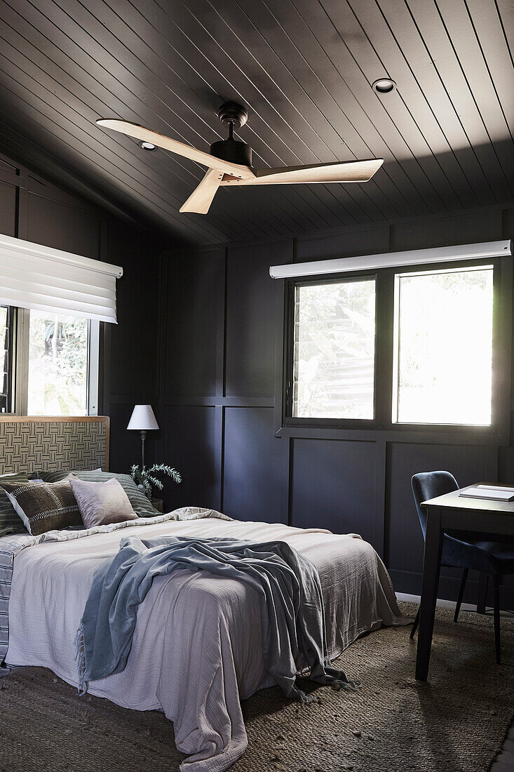 Double bed and study corner in the bedroom with dark brown wall