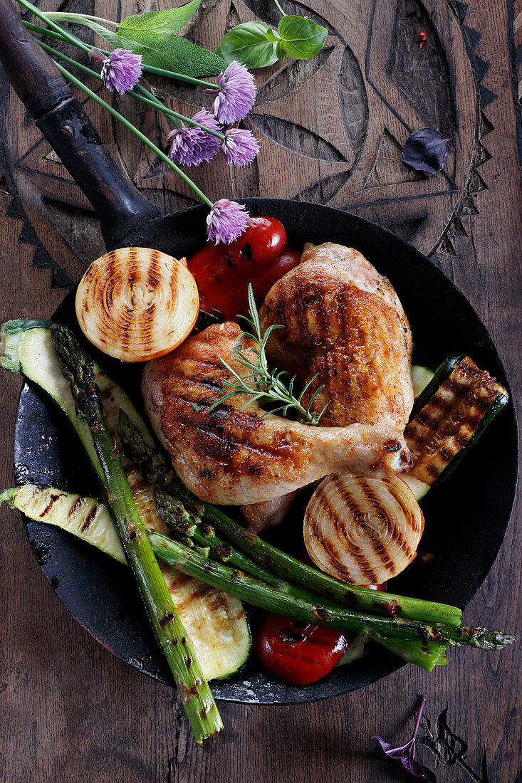 Grilled chicken and vegetables on a dark wooden table