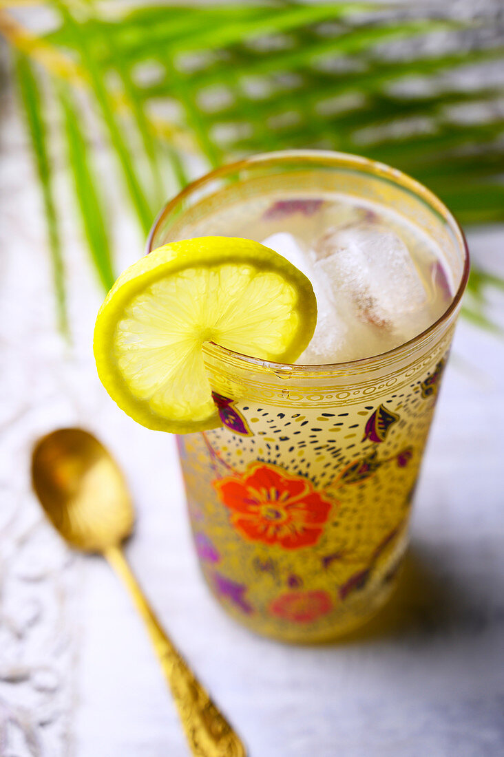 Spiked lemonade cocktail in a painted floral glass with a lemon slice garnish