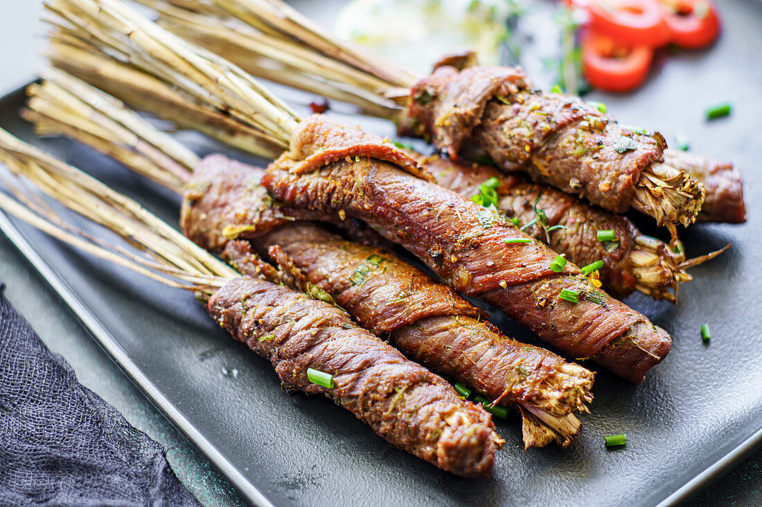 Marinated beef slices on lemongrass skewers on plate