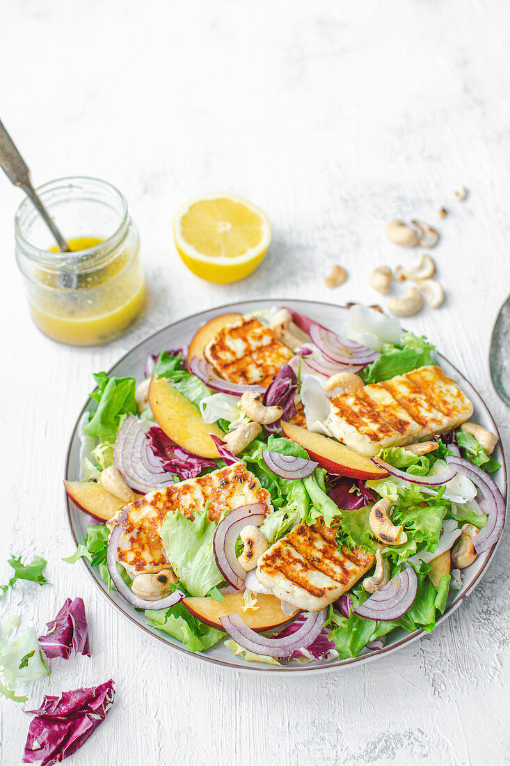 Salat mit gegrilltem Halloumi-Käse, Nektarinen, Zwiebeln und Cashewnüssen