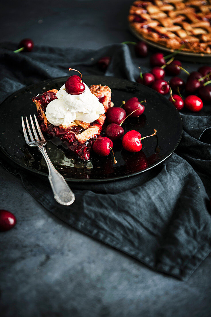 Ein Stück Kirschkuchen mit Teiggitter und Schlagsahne