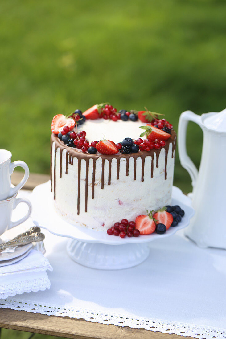 White cake with fresh berries on garden table