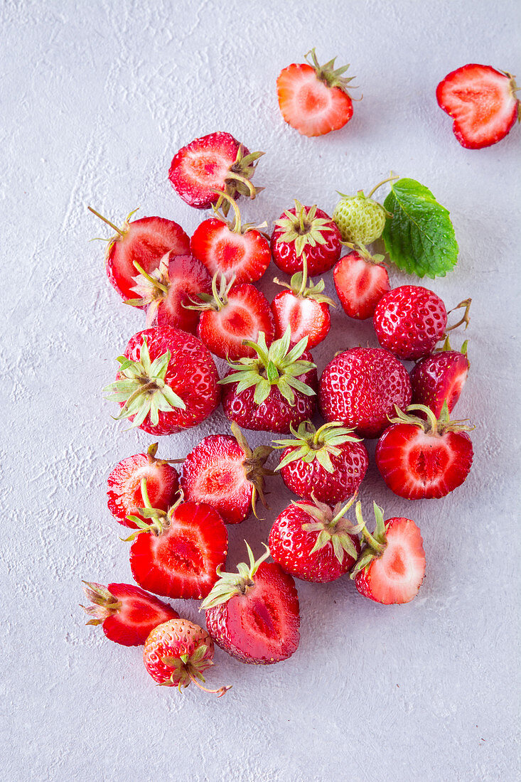 Frische Erdbeeren, teilweise halbiert auf hellem Untergrund