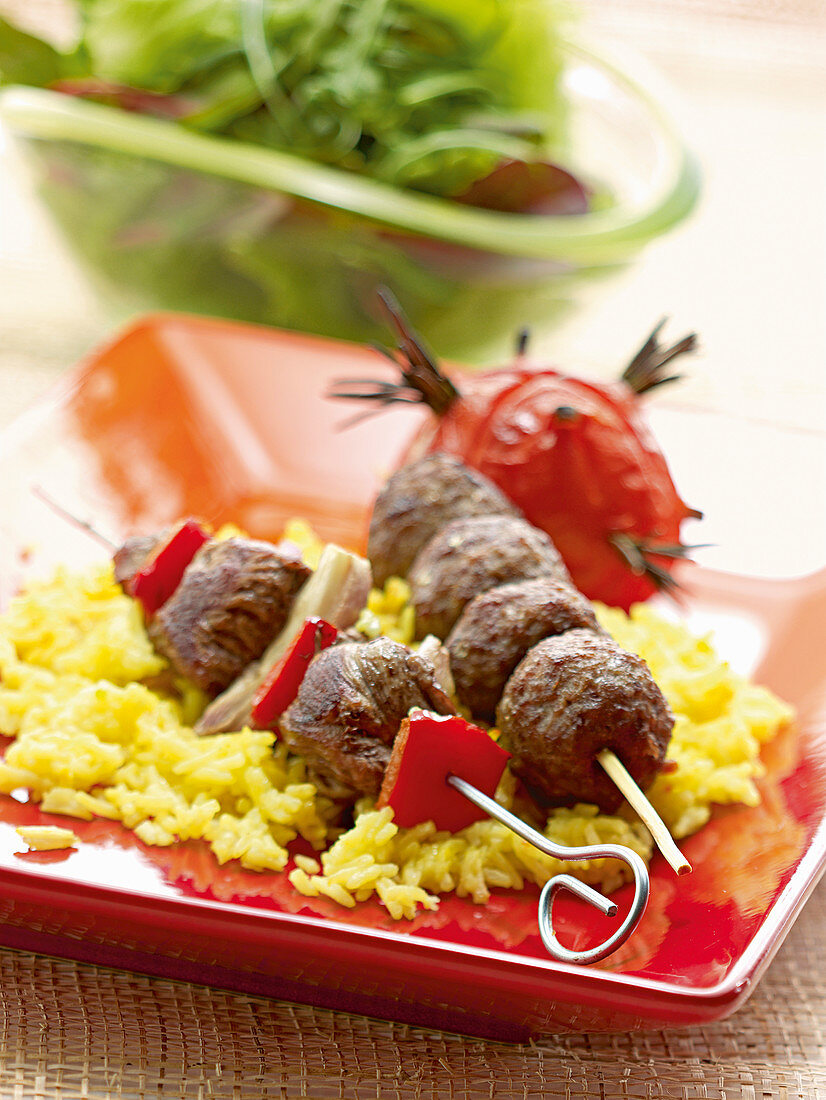 Deftige Fleischspieße auf Safranreis mit Grilltomate und Salat