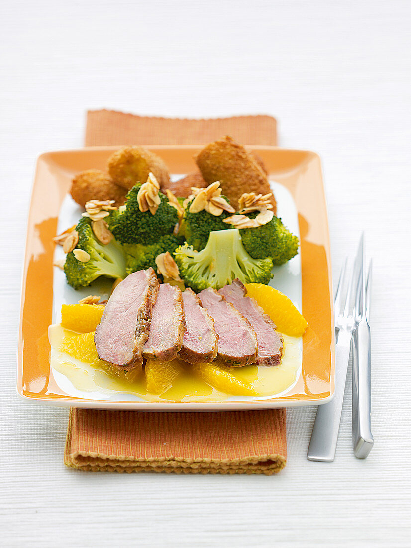 Slices of Duck breast on orange wedges with homemade croquettes and broccoli