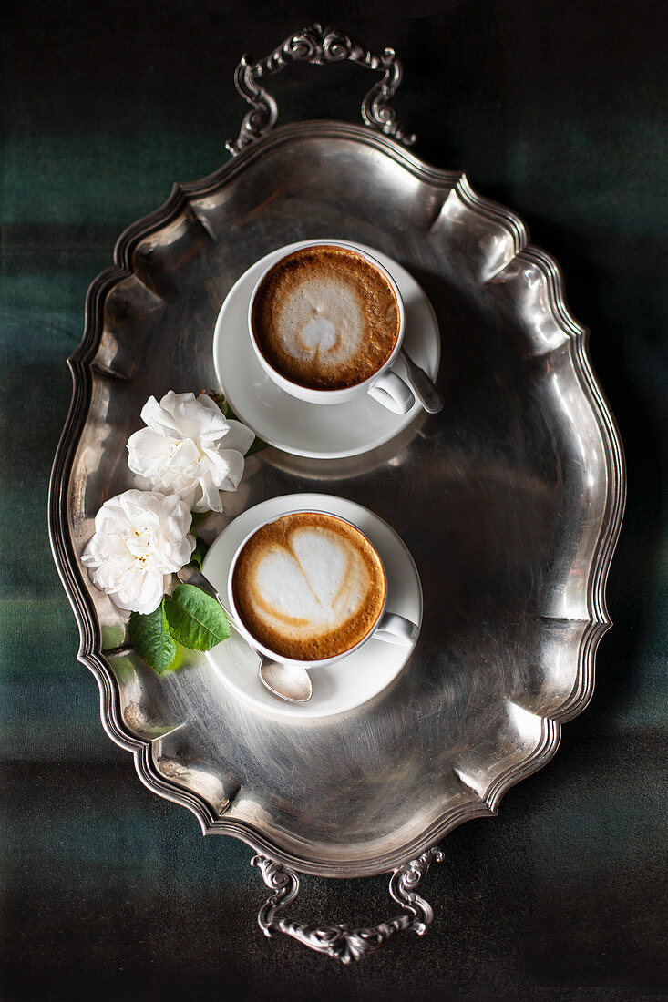 Zwei Tassen Cappuccino mit Milchschaum auf Silbertablett