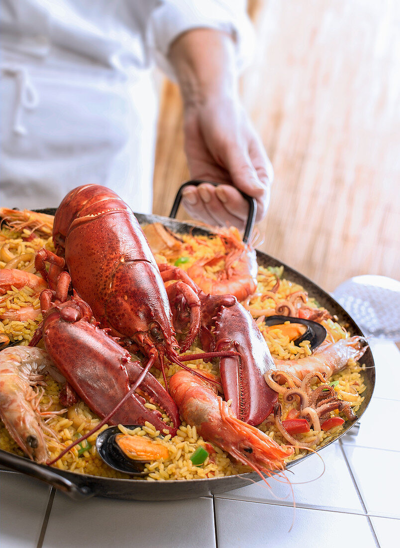 Chef serving paella with lobster