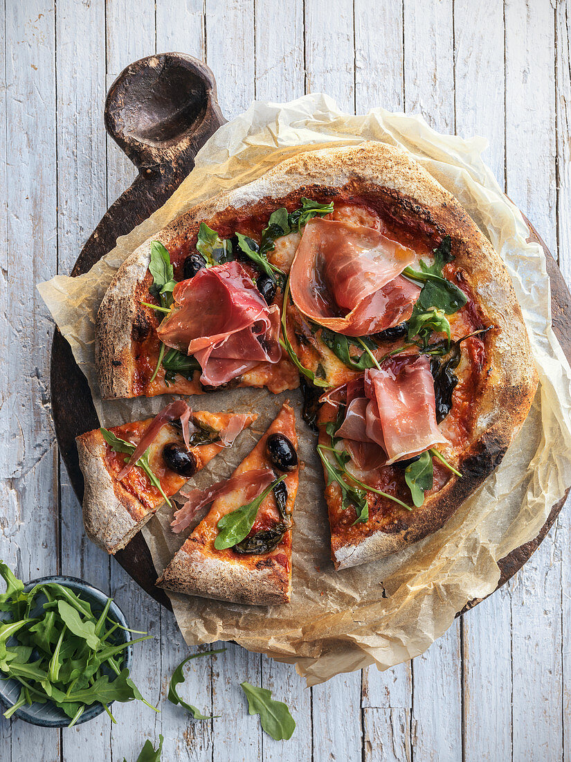 Prosciutto pizza with arugula and olives