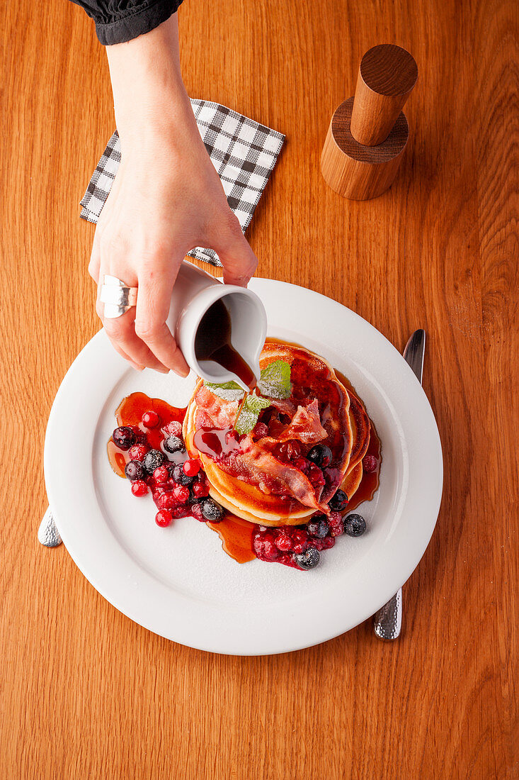 Blueberry pancakes with bacon, berries, and maple syrup