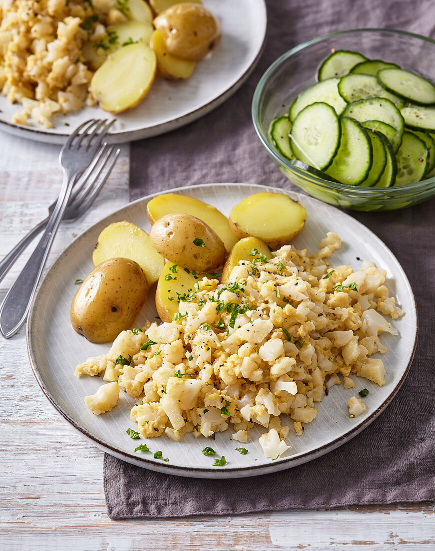 Cauliflower with scrambled eggs, baked potatoes, and cucumber salad