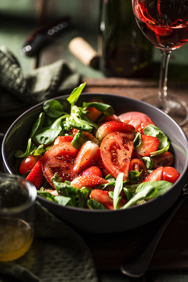 Tomaten-Erdbeer-Salat mit Feldsalat und Basilikum serviert mit Honigdressing